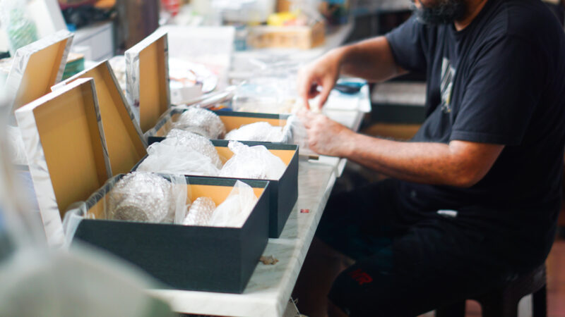 Man packing items in boxes, possibly for print and direct mail services.